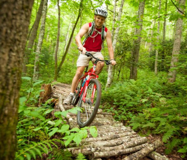 Guest biking on a log bridge