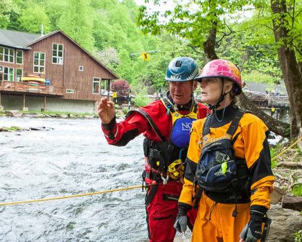 Instructors and students scouting a rapid during swiftwater rescue course