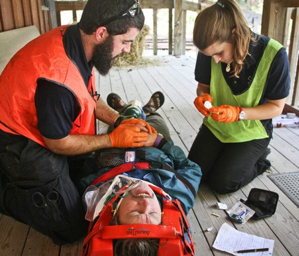 Two people tending to a person in a stretcher